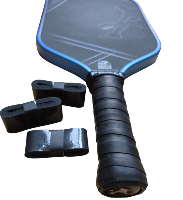 A pickleball paddle with a black textured face, blue edge trim, and a black wrapped overgrip, shown alongside three black overgrip tapes rolls on a plain white background.