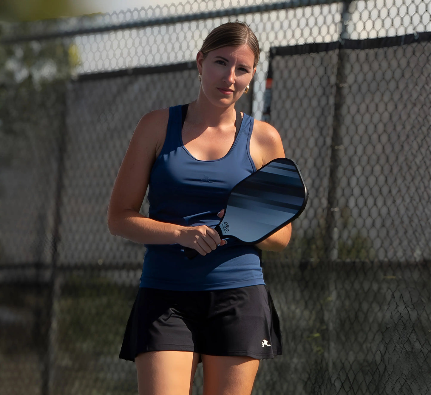Woman wearing a Blue tank top holding a paddle on a pickleball court Bleu