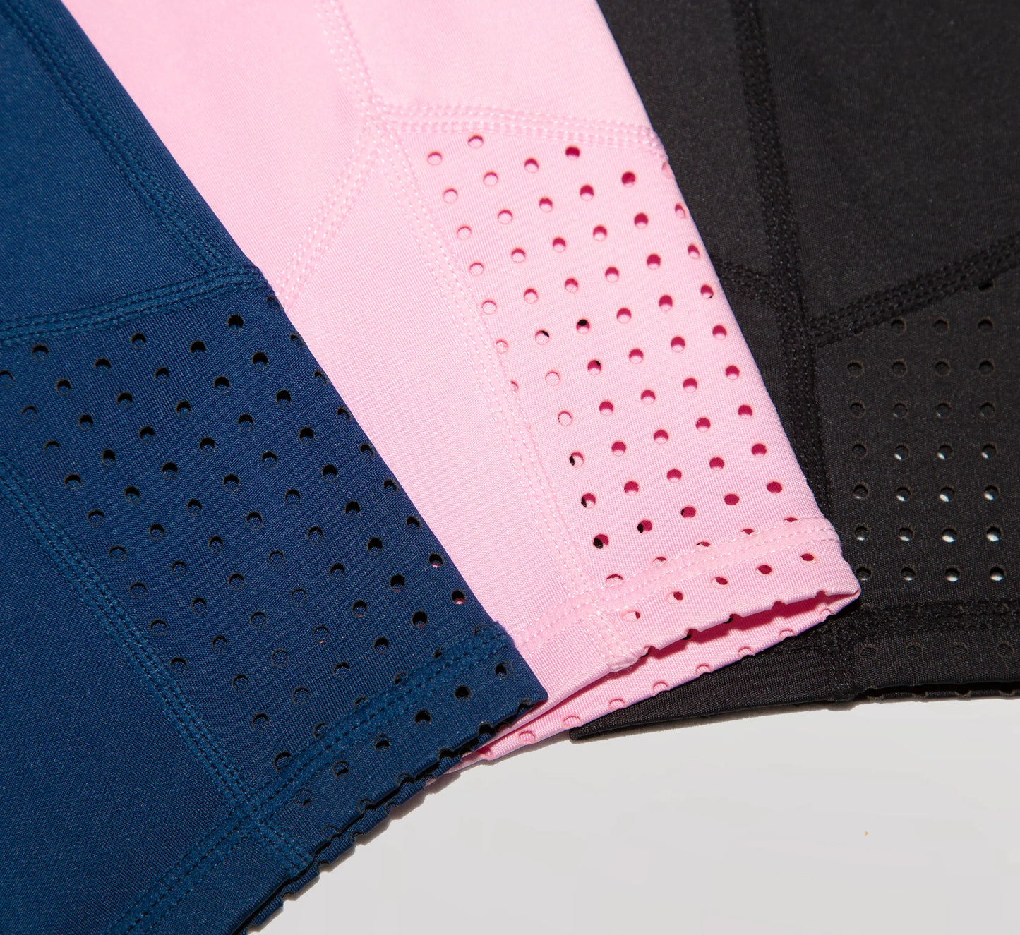 Three pieces of legging fabric in blue, pink, and black on a light gray background