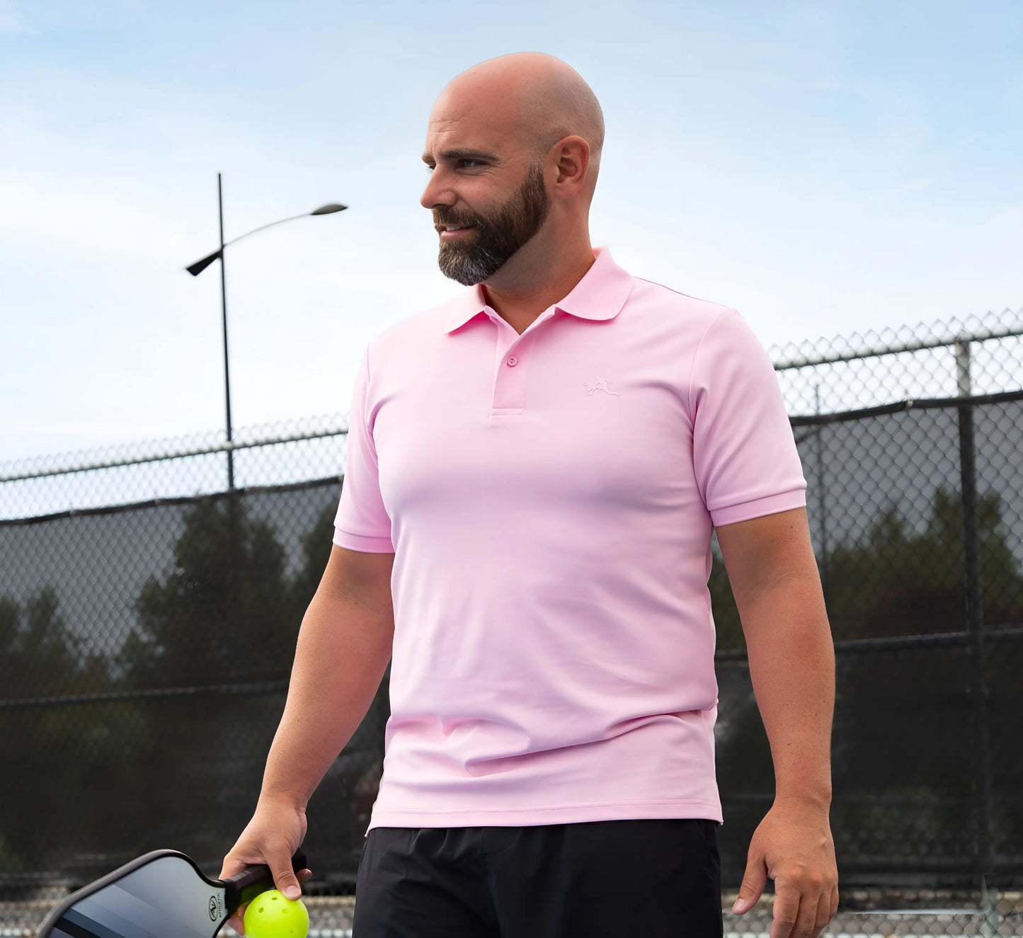 Man in a Pink polo shirt holding a pickleball ball on a pickleball court Rose