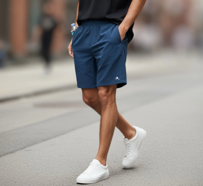 Person wearing blue shorts and white sneakers on a street.