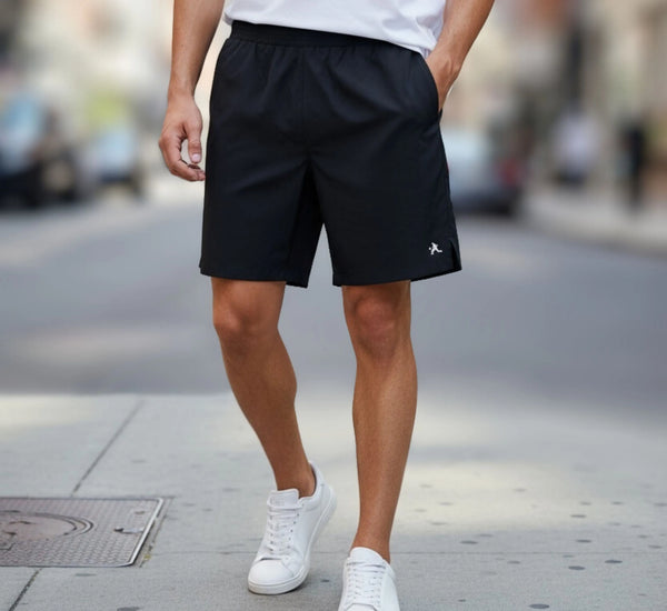 Person wearing black shorts and white sneakers on a city street.