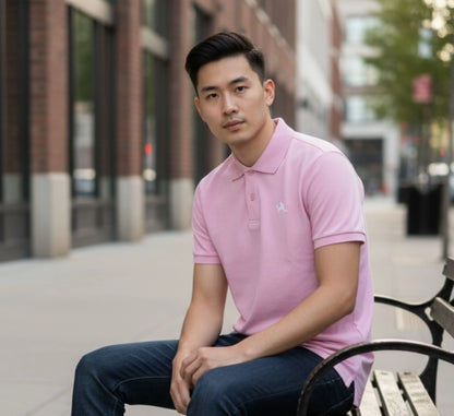 Man wearing a pink polo shirt sitting on a bench outdoors.