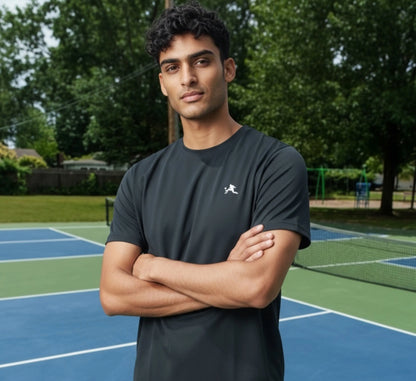 Man standing on a pickleball court with trees in the background