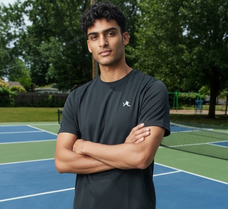 Man standing on a pickleball court with trees in the background