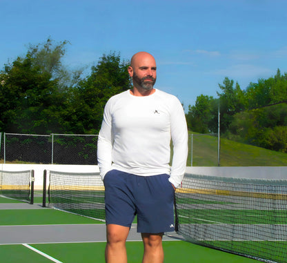 Man standing on a pickleball court wearing a White long-sleeve shirt and blue shorts Blanc