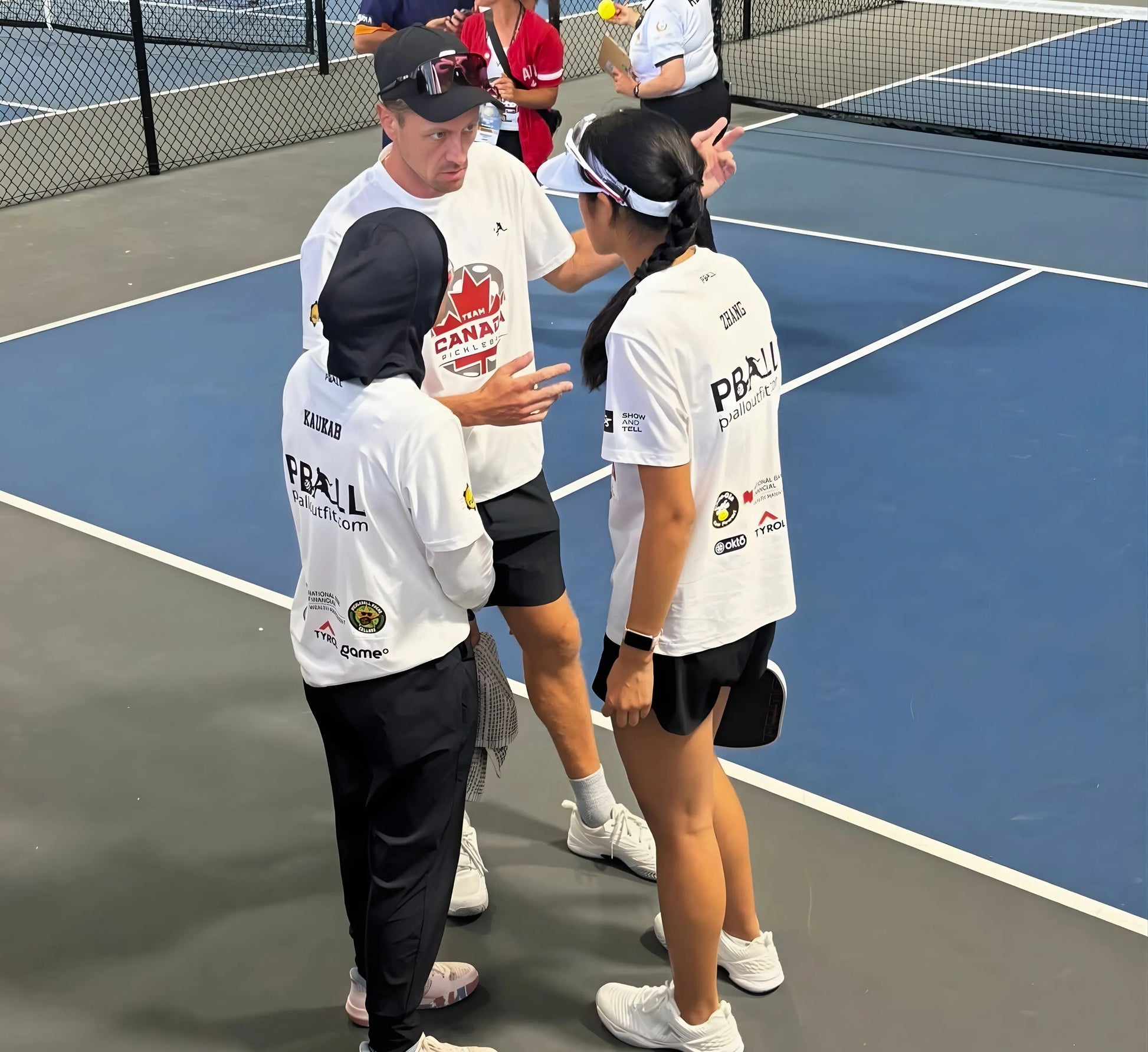 People on a pickleball court with 'PBALL' branding