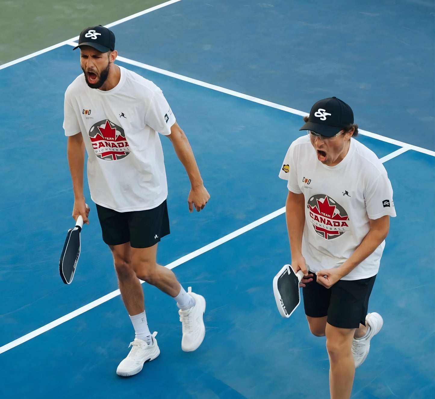 Two pickleball players on a court wearing Canada-themed shirts and hats.