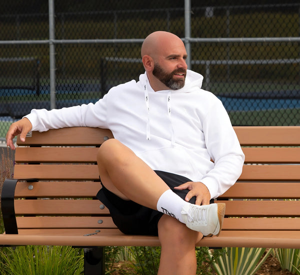 Man sitting on a bench wearing a White hoodie and shorts Blanc