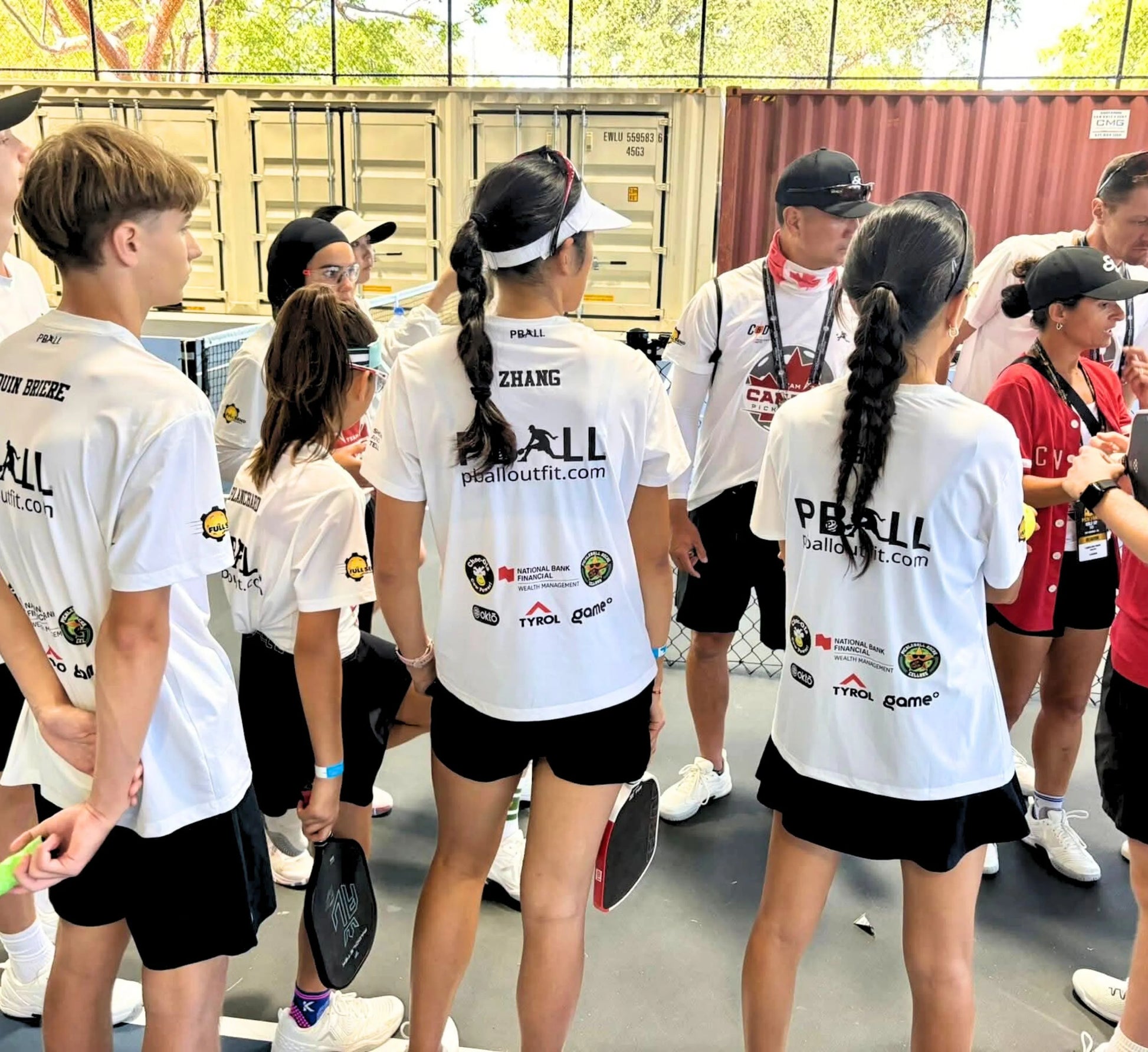 Group of people wearing white shirts with logos, standing in a line.