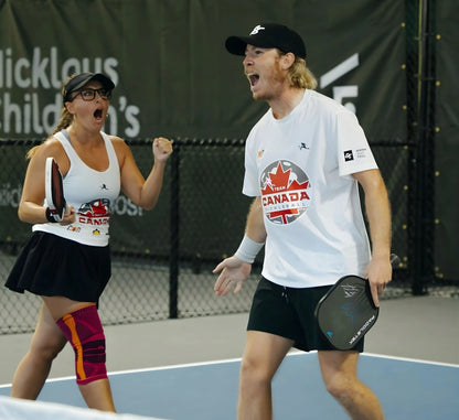 Two pickleball players on a court with a branded background