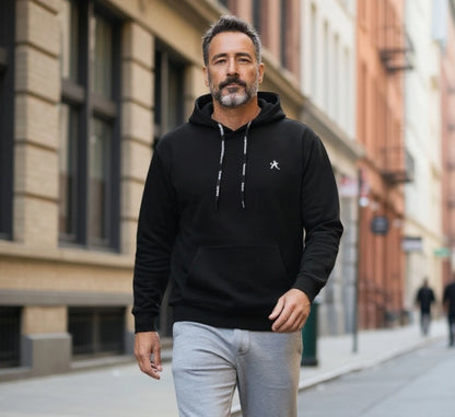 Man wearing a black hoodie with a logo on a city street