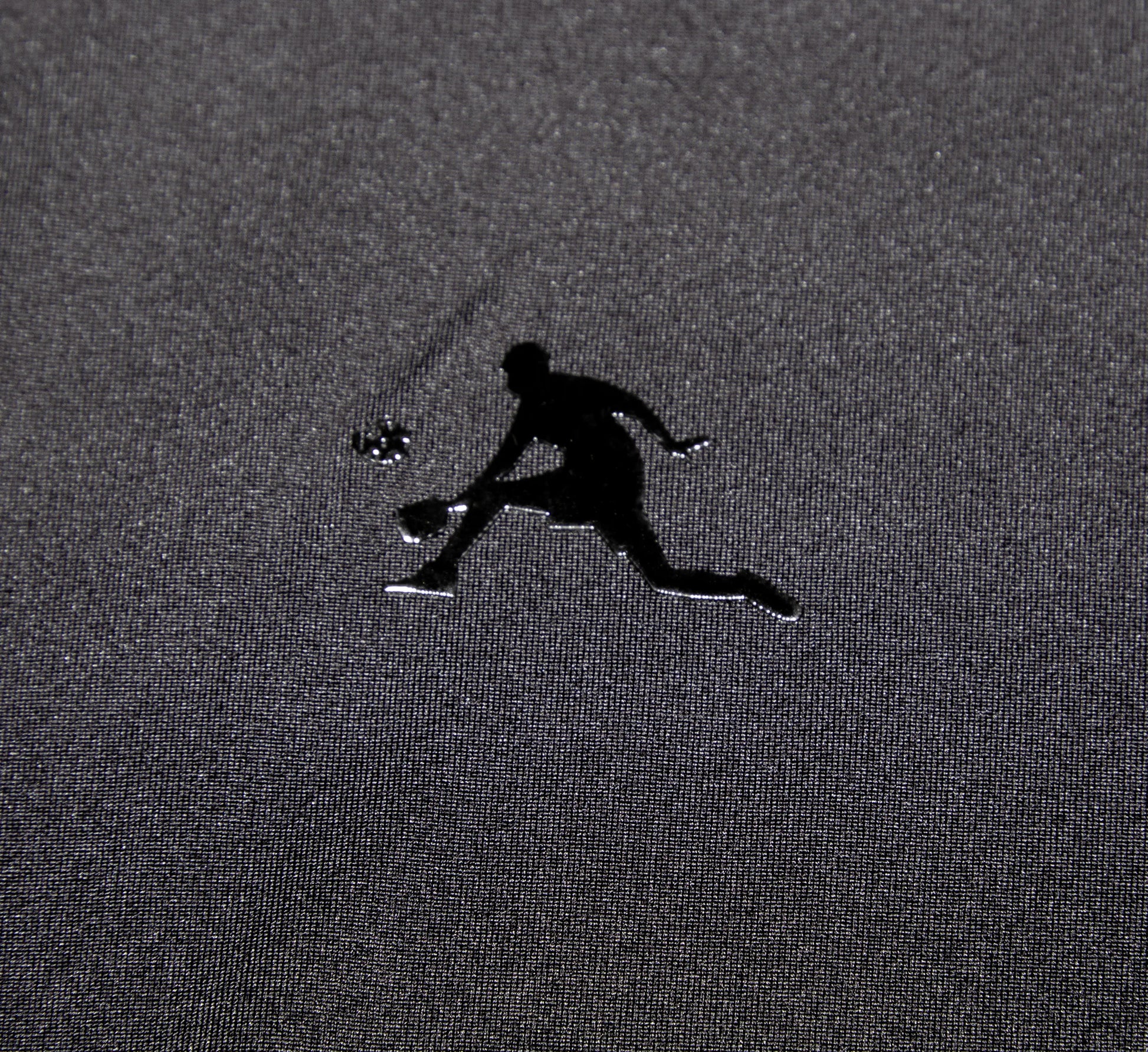 Black logo of a pickleball player on a textured gray surface Noir