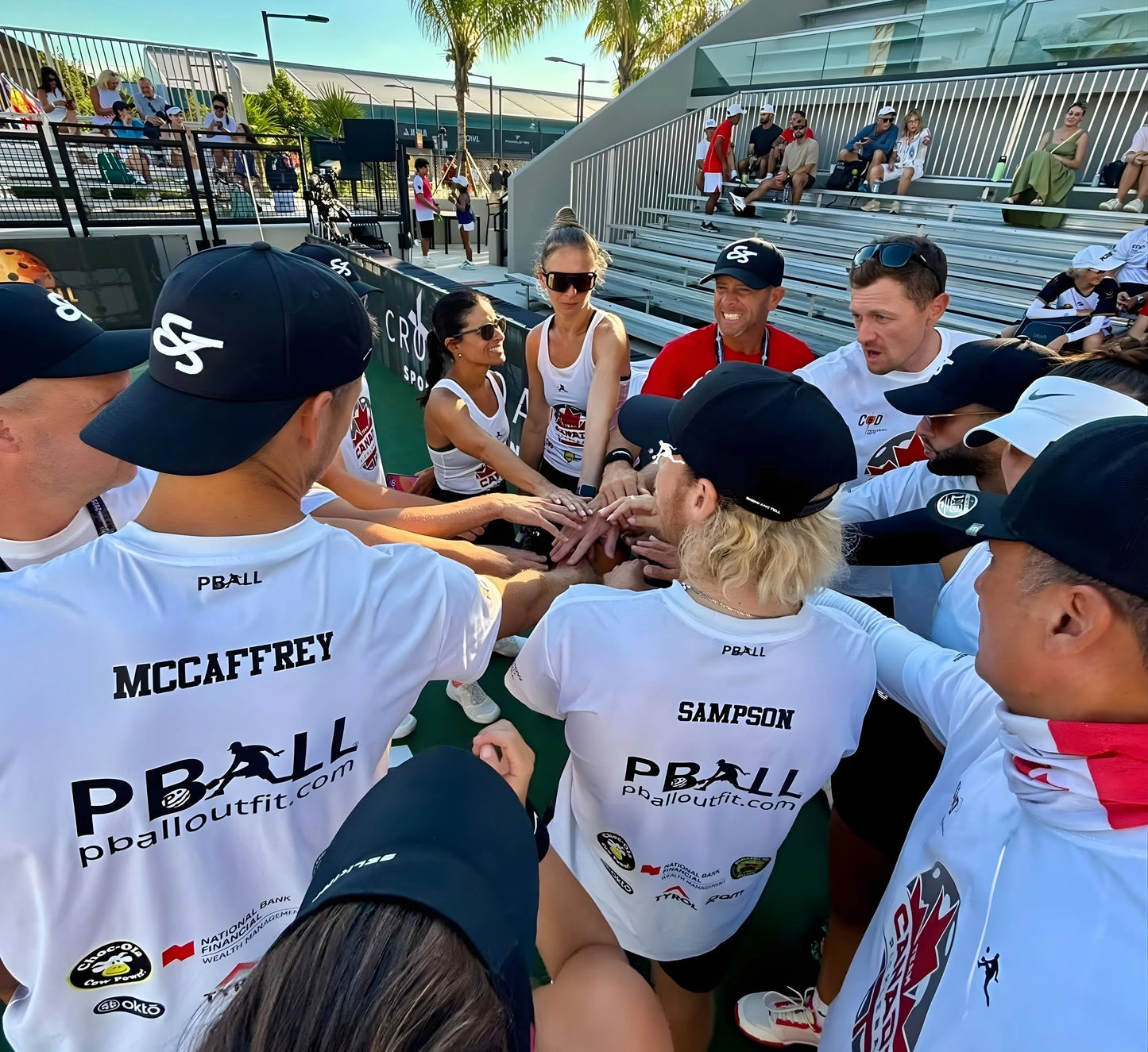 Group of people in white PBALL pickleball jerseys with 'PBall' branding, sitting together outdoors.