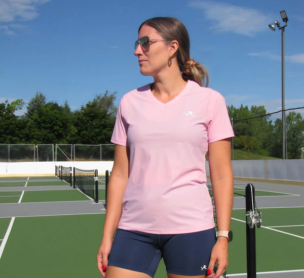 Woman in Pink t-shirt and sunglasses standing on a pickleball court Rose